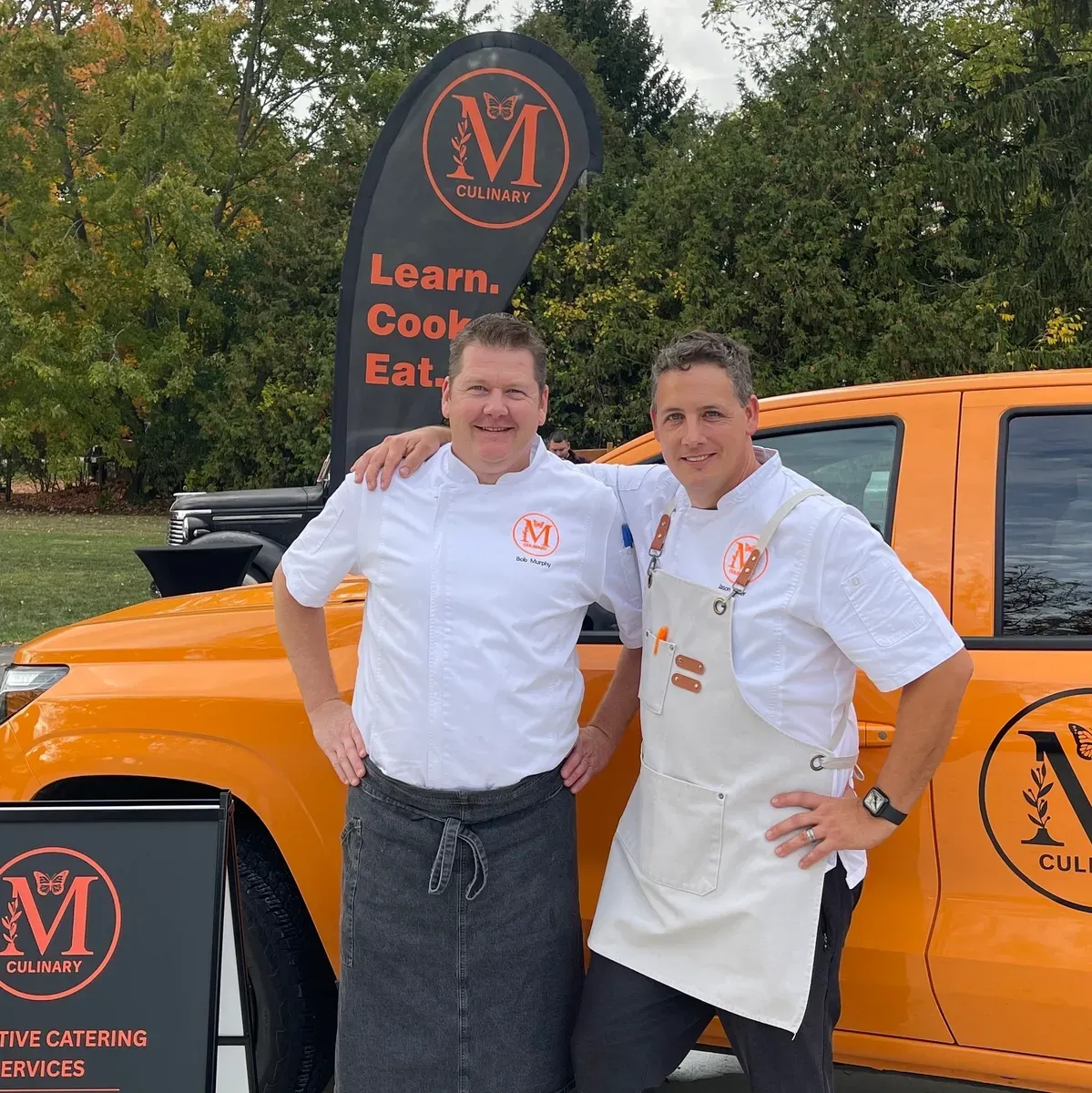 Monarch Culinary chefs in whites beside the branded catering van at an outdoor event