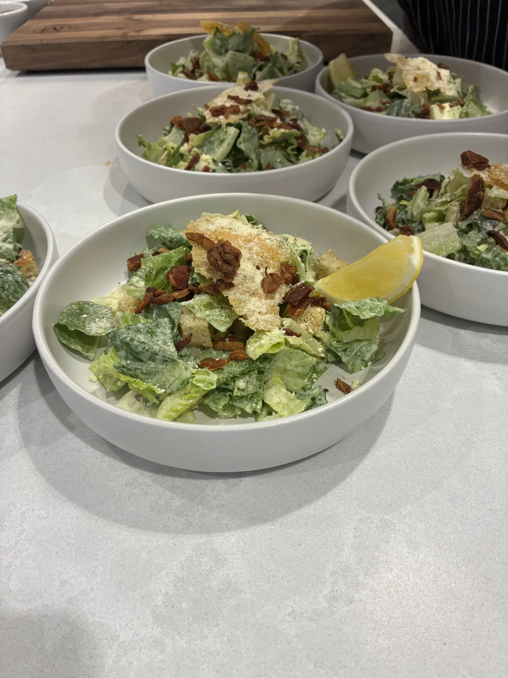 Caesar salad bowls plated with lemon wedges