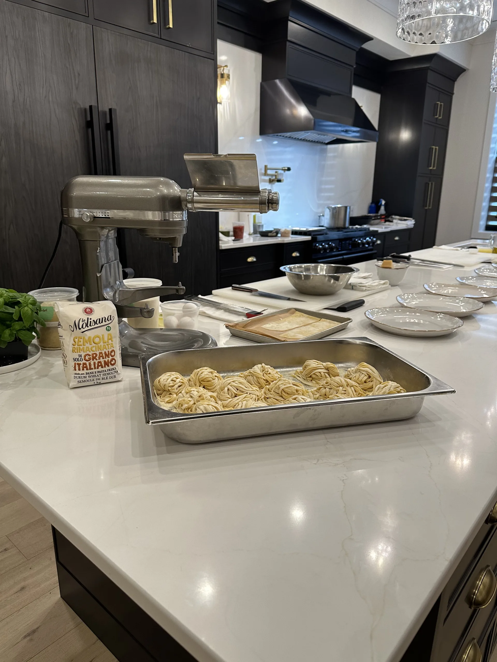 Trays of prepared food on the studio counter beside a pasta machine