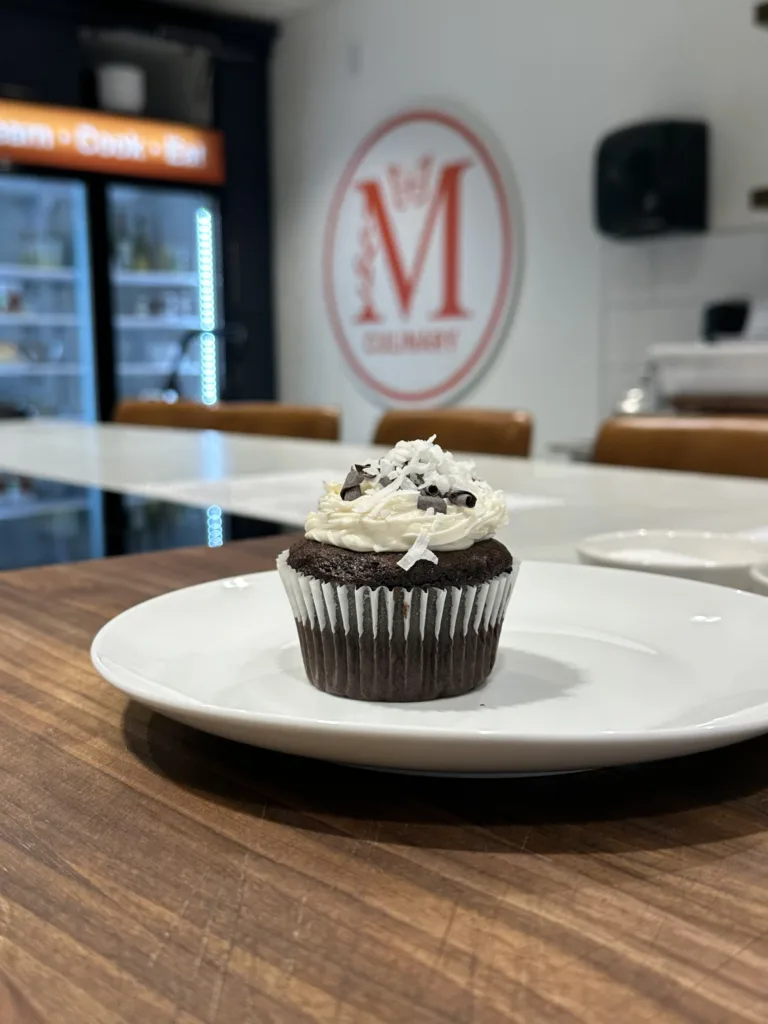 Chocolate cupcake topped with cream, plated at the Monarch Culinary Studio