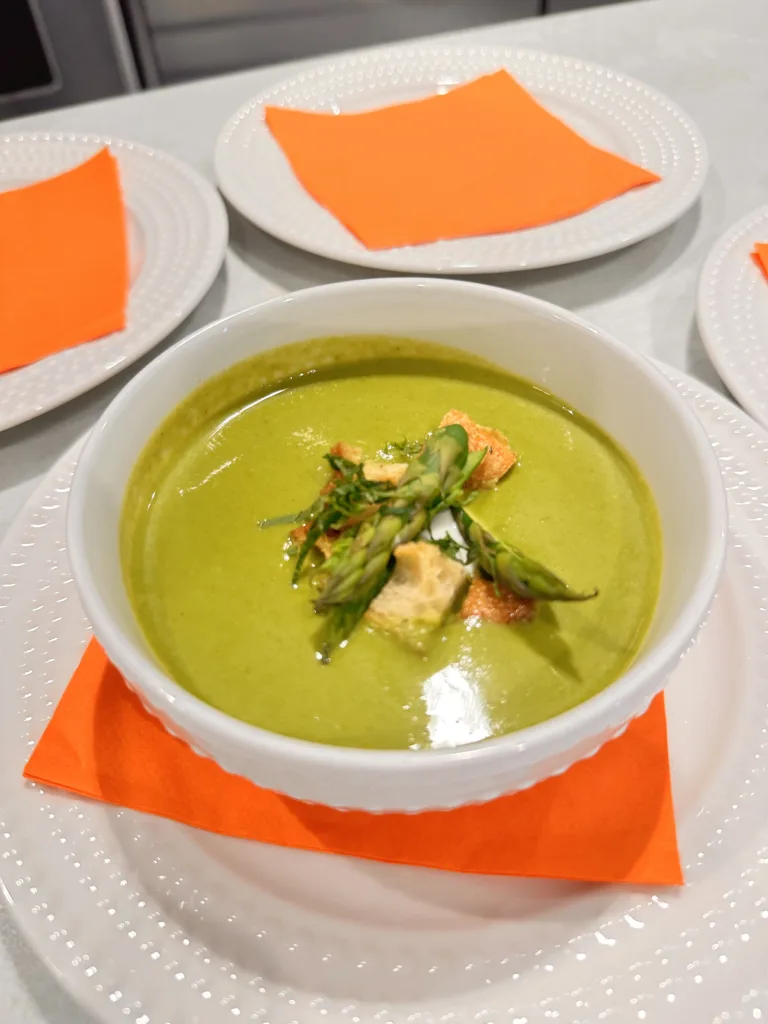 Bowl of green pea soup, garnished and served on an orange napkin