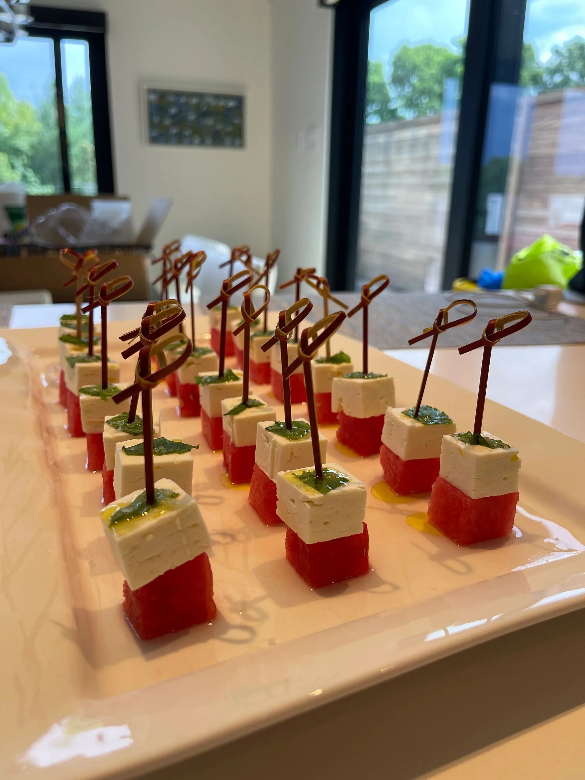 Watermelon and feta skewers with herb drizzle, served as a fresh summer appetizer on a white platter