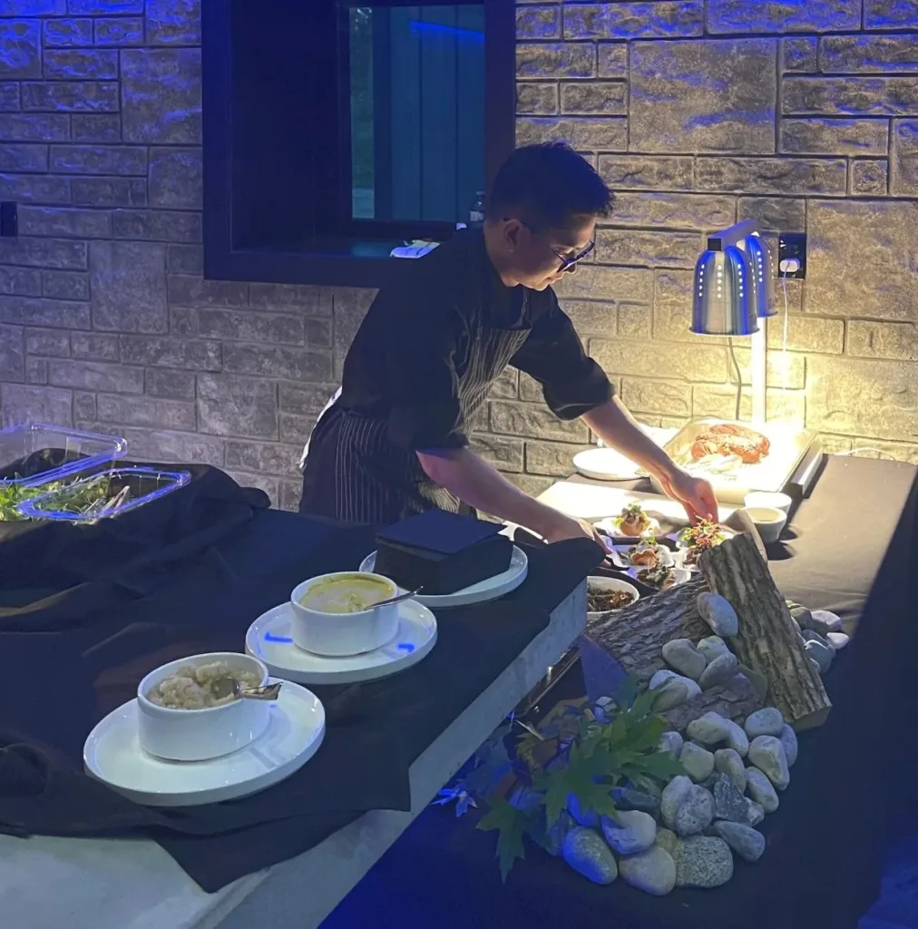 Chef preparing plated appetizers at a live carving station during a catered event