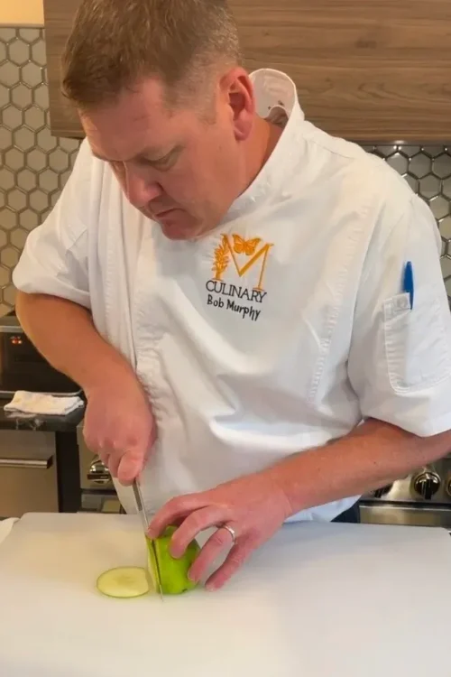 Monarch Culinary chef slicing produce at the studio counter during a class