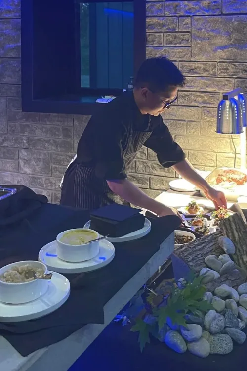 Chef preparing plated appetizers at a live carving station during a catered event
