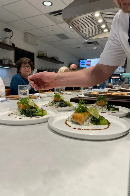 Chef plating salmon over rice during a class at the Monarch Culinary Studio